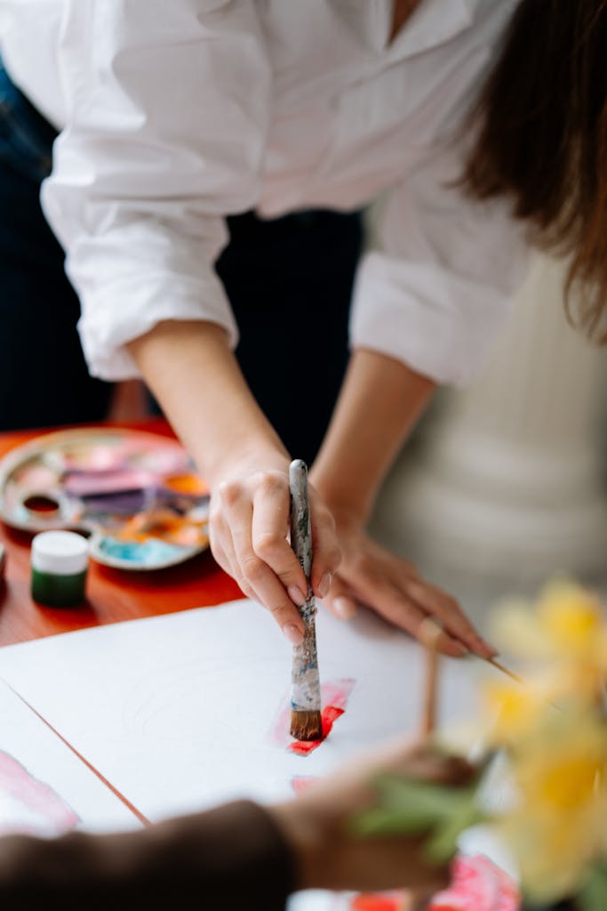 A close-up of an artist's hand using a paintbrush on canvas, highlighting creativity.