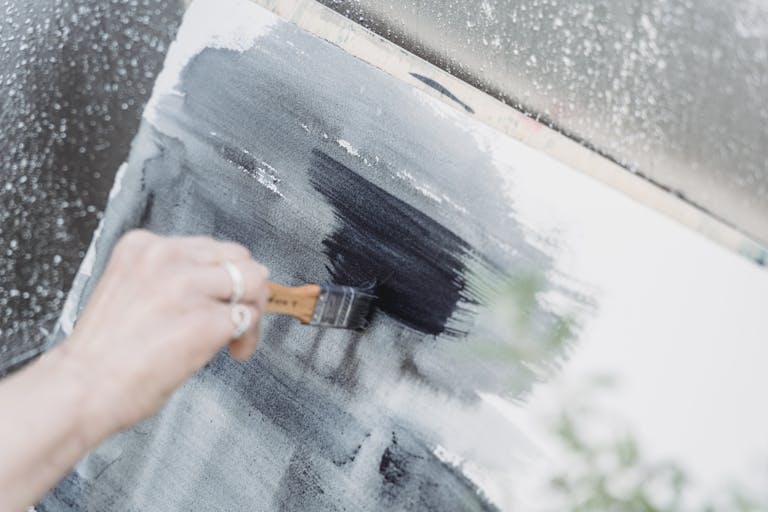 A close-up view of an artist painting with brush strokes on a canvas, showcasing creativity.