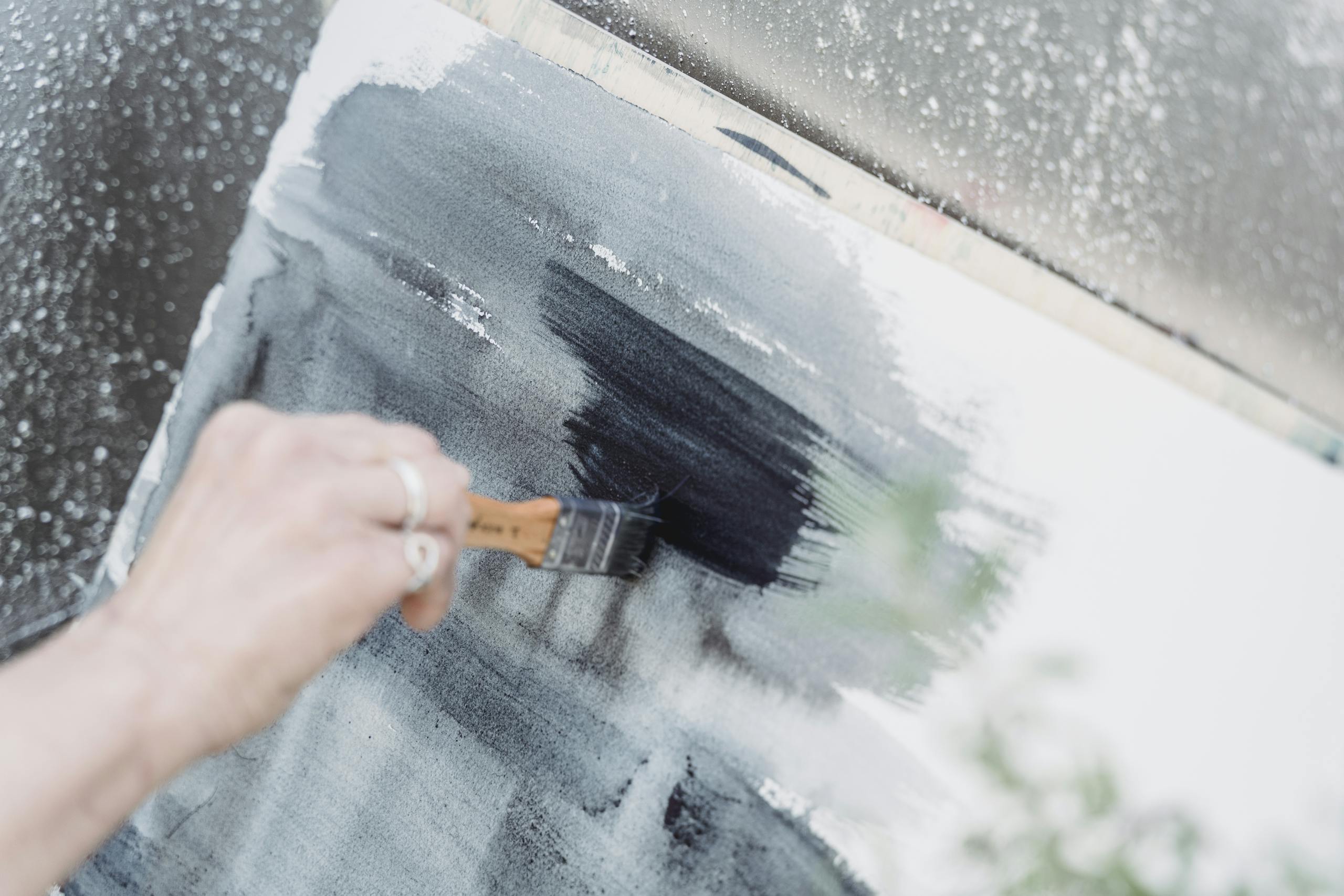 A close-up view of an artist painting with brush strokes on a canvas, showcasing creativity.