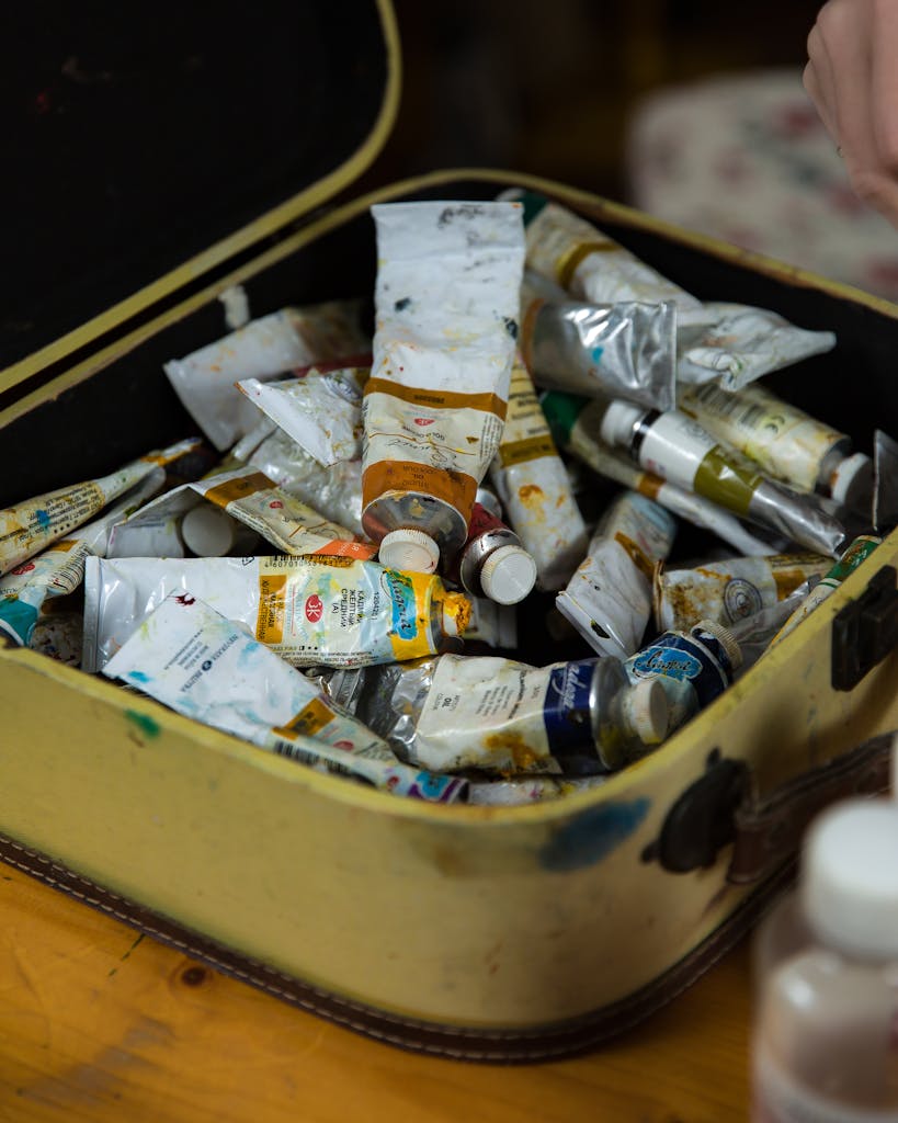 A collection of paint tubes in a vintage box, ideal for creative art projects.