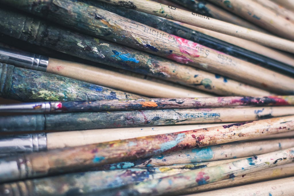 A detailed look at a collection of paintbrushes covered in colorful paint remnants.