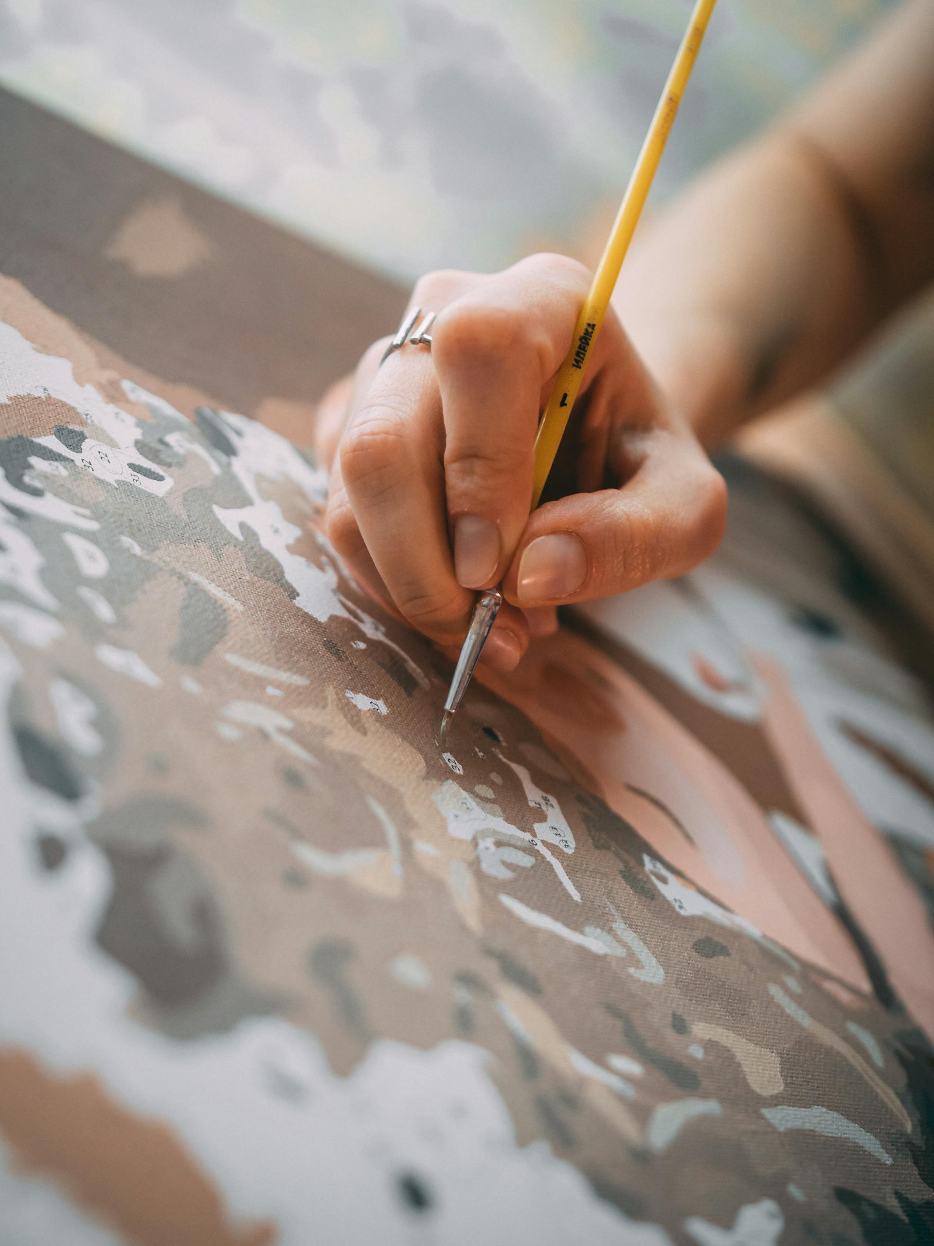 A detailed view of a hand carefully painting on a canvas, showcasing artistic creativity and technique.