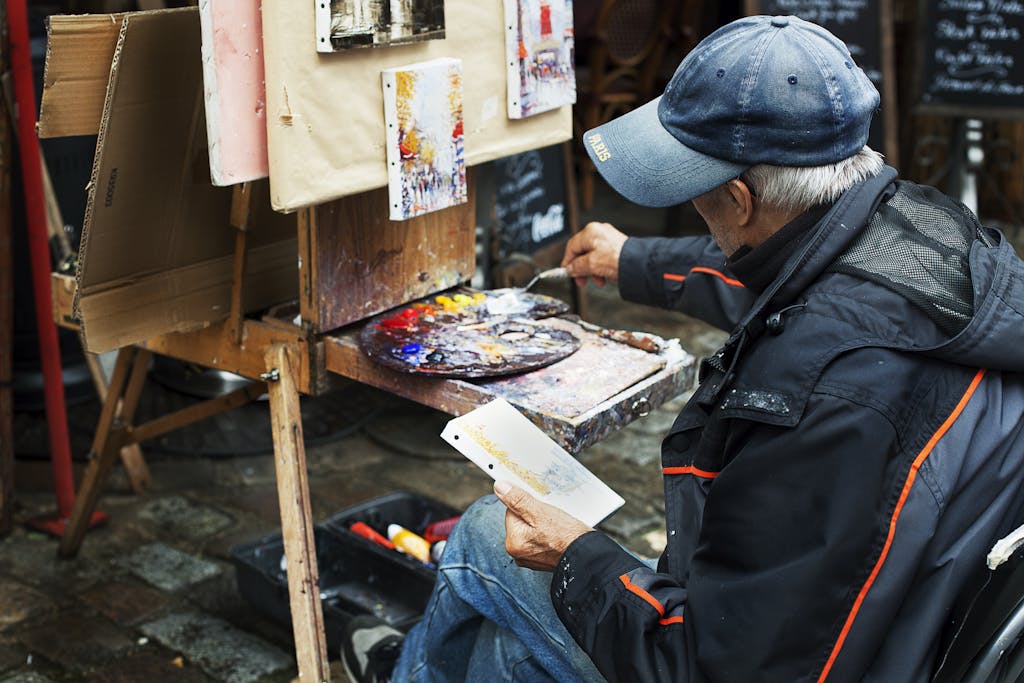 A street artist paints colorful abstracts on canvas, showcasing vibrant creativity in an outdoor setting.