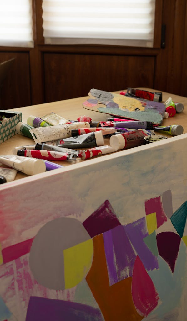 A variety of colorful paints and brushes on an artist's table, perfect for creative projects.