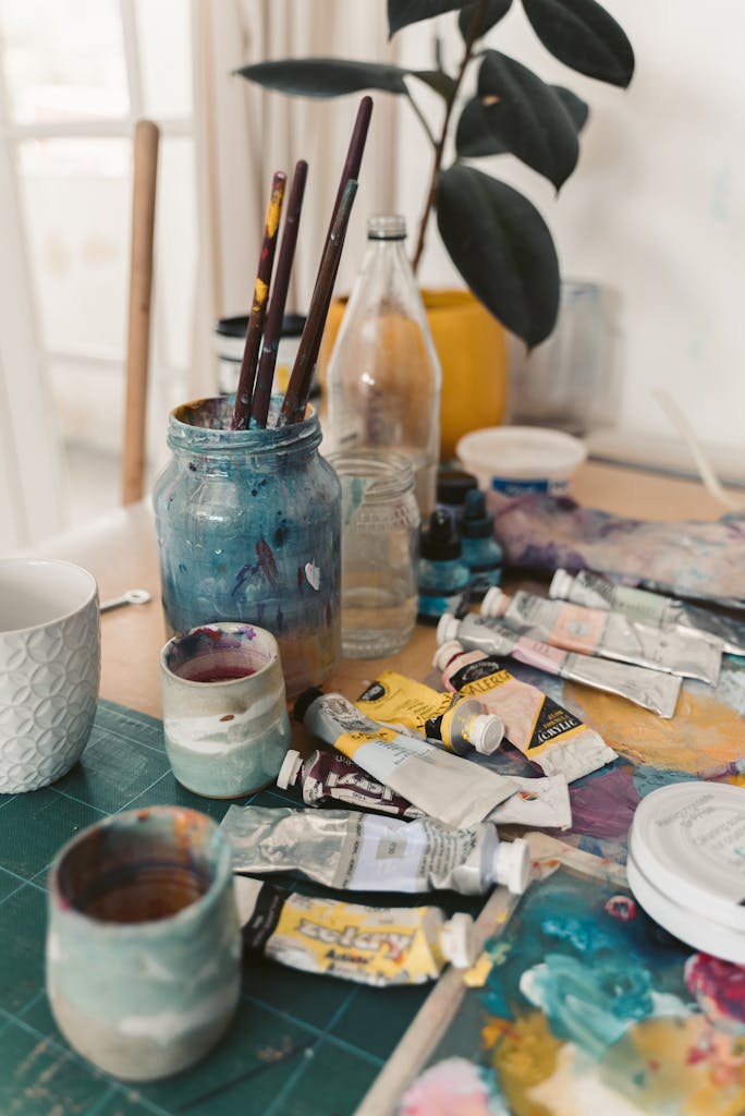 A vibrant display of art supplies including oil paints and brushes on a wooden table in a creative studio.