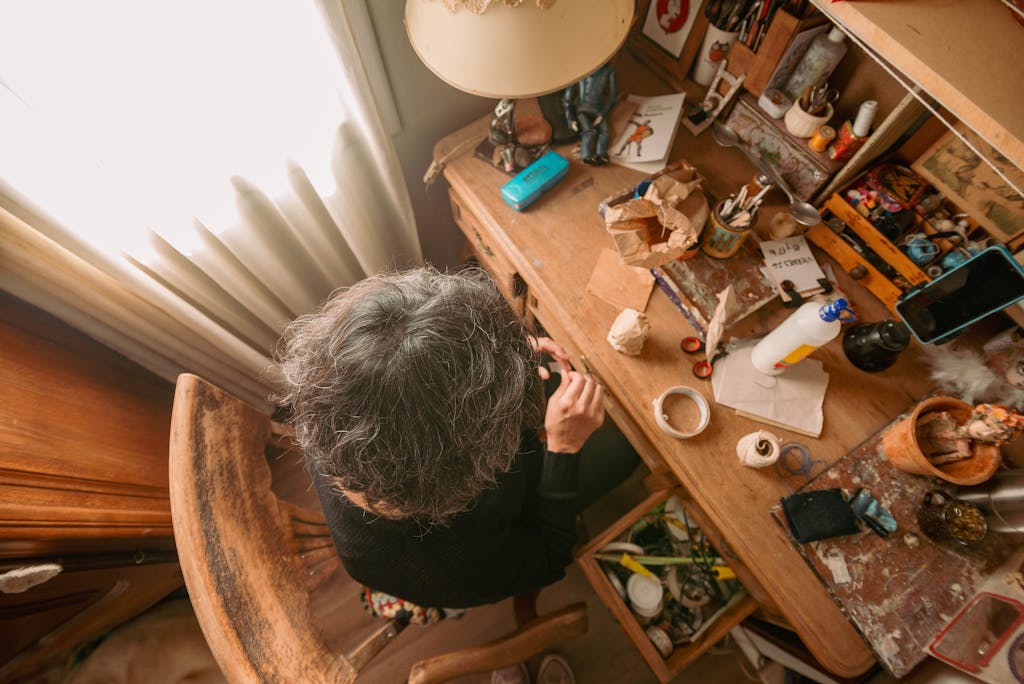 Aerial view of an artist at work in a cozy, cluttered studio space.