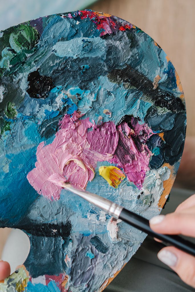 An artist mixes vibrant colors on a palette with a paintbrush, showcasing creativity.