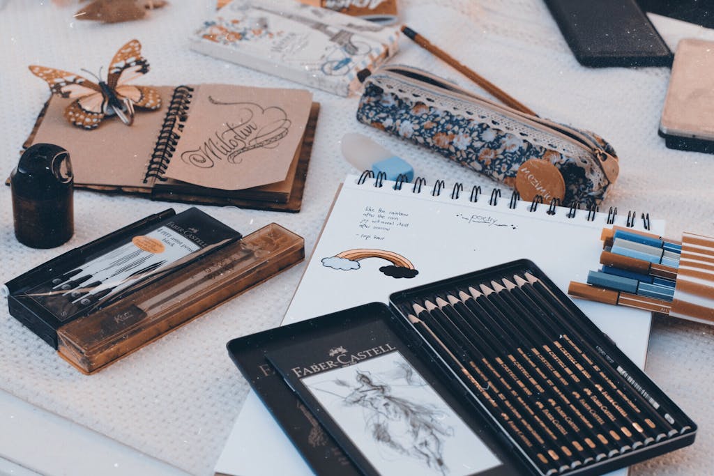 Art supplies including pencils, pens, and sketchbooks arranged on a table for creativity.