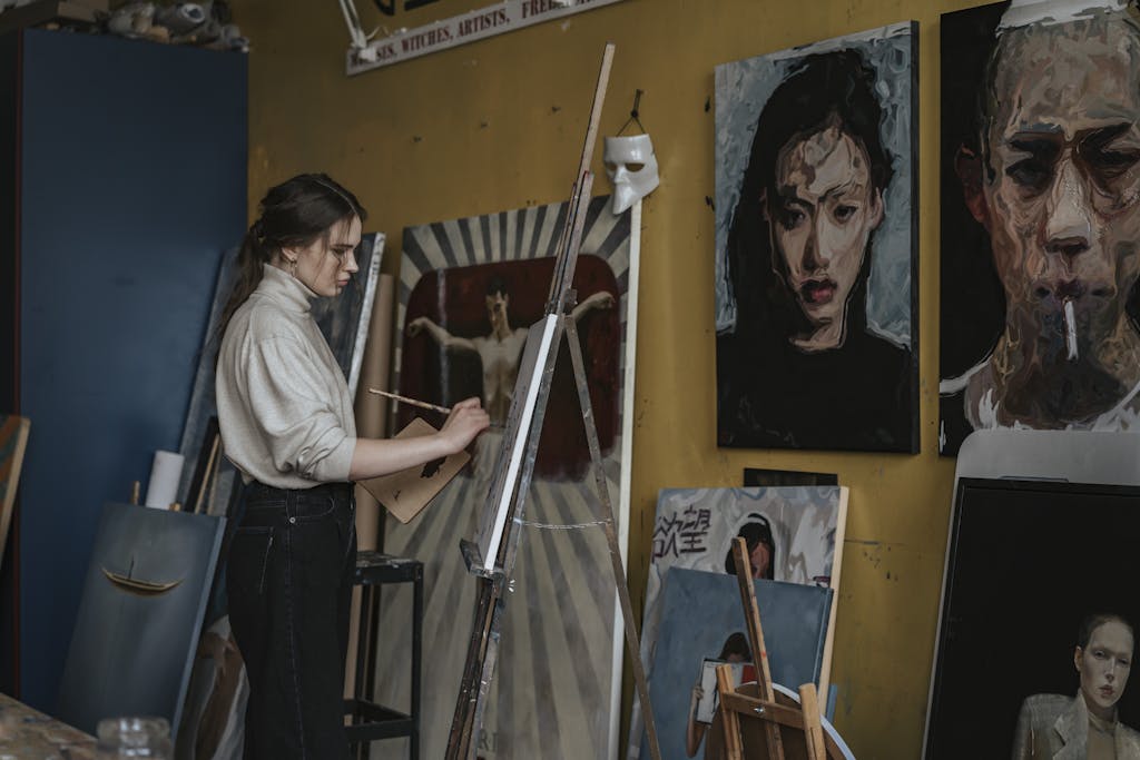 Artist creates paintings in a studio surrounded by expressive portrait artworks.