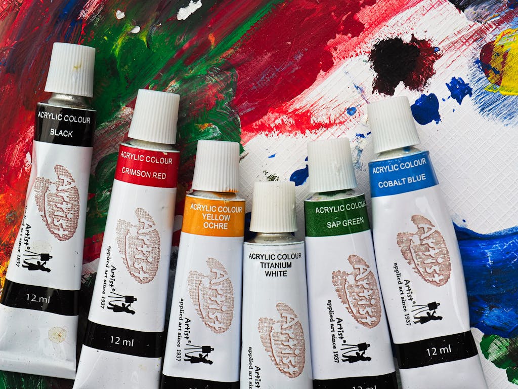 Assorted acrylic paint tubes displayed on a vividly painted canvas, showcasing creativity.