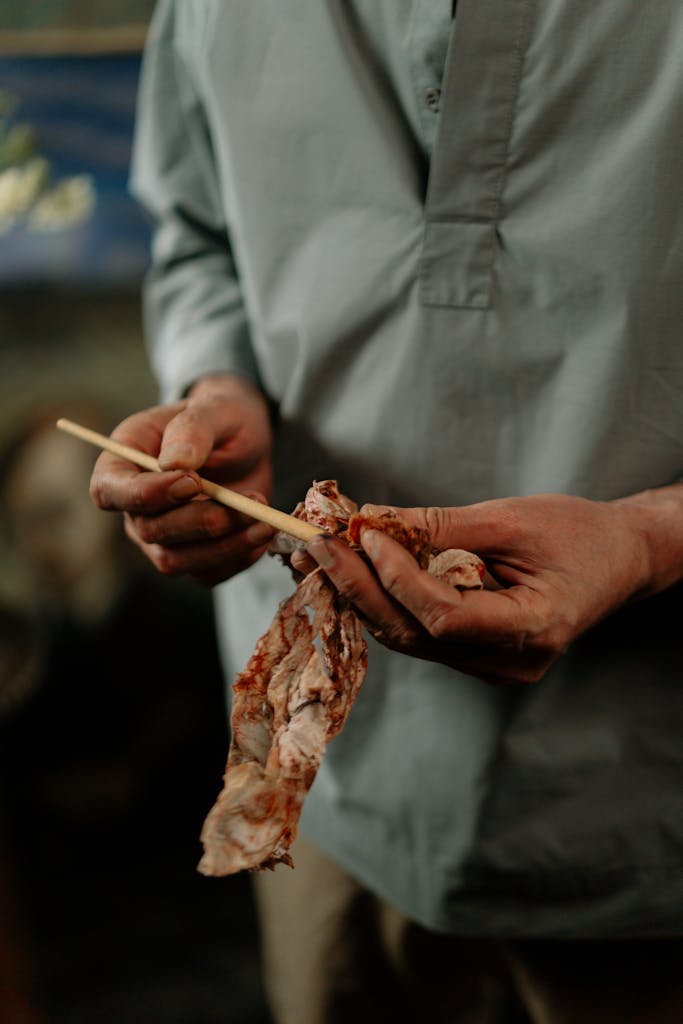 Close-up of an artist cleaning a paintbrush with a rag inside a studio.