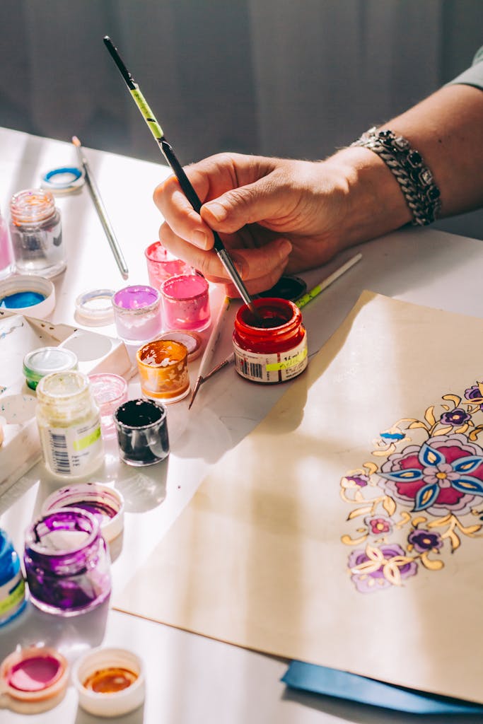 Close-up of hand painting with vivid colors on a sheet, showcasing creativity and detail.