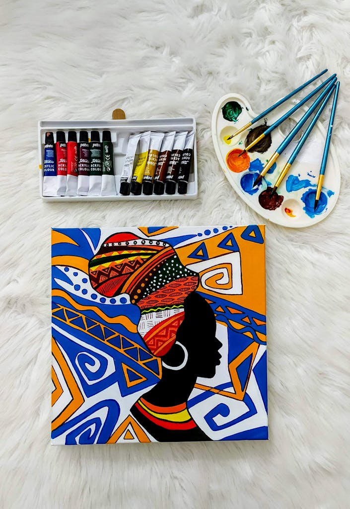 Colorful African-themed canvas with paints and brushes on a plush background.