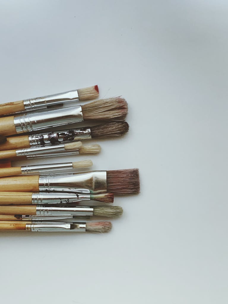Minimalist arrangement of various brushes on a clean white surface.