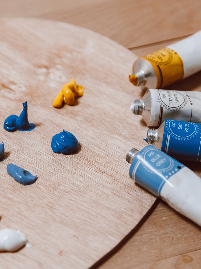 Multiple tubes of blue and yellow paint on a wooden palette, ready for artistic creation.