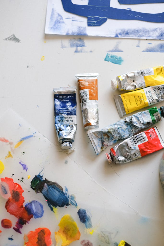 Top view of a creative art workspace with paint tubes and palettes.