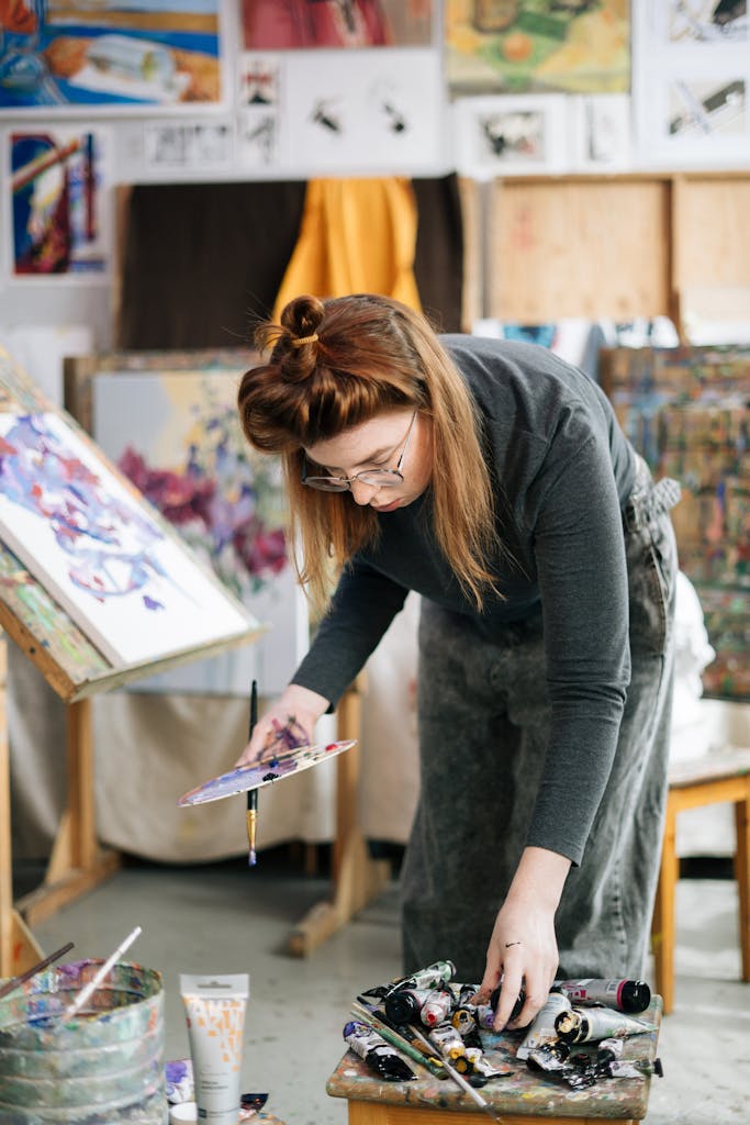 Woman artist choosing paint colors in a vibrant workshop setting.